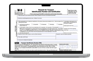 A fillable W-9 form in PDF is open on the laptop